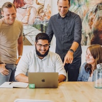 Coworkers smiling and collaborating around a laptop
