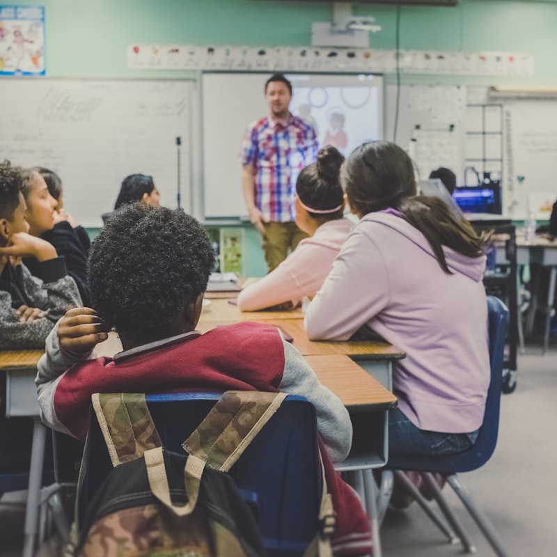Students in a classroom with a teacher presenting